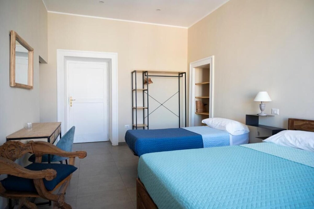 Ein Hotelzimmer mit zwei Betten, einem Schreibtisch, einem Stuhl, einem Kleiderschrank und einem Spiegel.