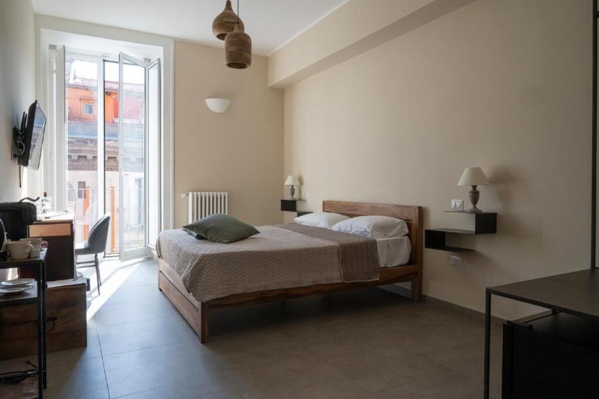 Ein Schlafzimmer mit einem Bett, Nachttischlampen, einem Schreibtisch und einem Sessel.