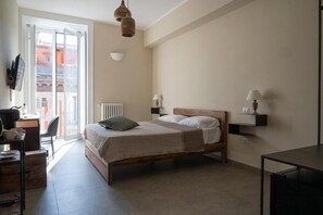 A bedroom with a bed, bedside lamps, a desk, and a chair. - Bellavista Relais (Napoli)