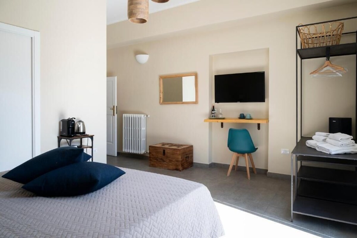 Ein Schlafzimmer mit Bett, Schreibtisch, Stuhl, Fernseher und Kleiderschrank.