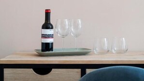 A wooden-framed mirror on a wall, a wine bottle, and two glasses on a wooden table. - Bellavista Relais (Napoli)