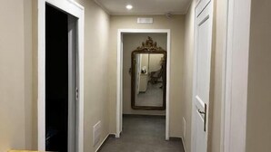 A hallway with a wooden bench, a mirror, and a door at the end. - Bellavista Relais (Napoli)