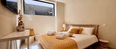 A modern bedroom with a bed, bedside table, and a window.