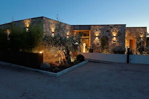 A modern building with stone walls and warm lighting, surrounded by landscaped gardens. - VILLA DOLCE VECCHIA—Exceptional Villa in Cala Rossa—Beach within walking distance, sleeps 10 (Lecci)