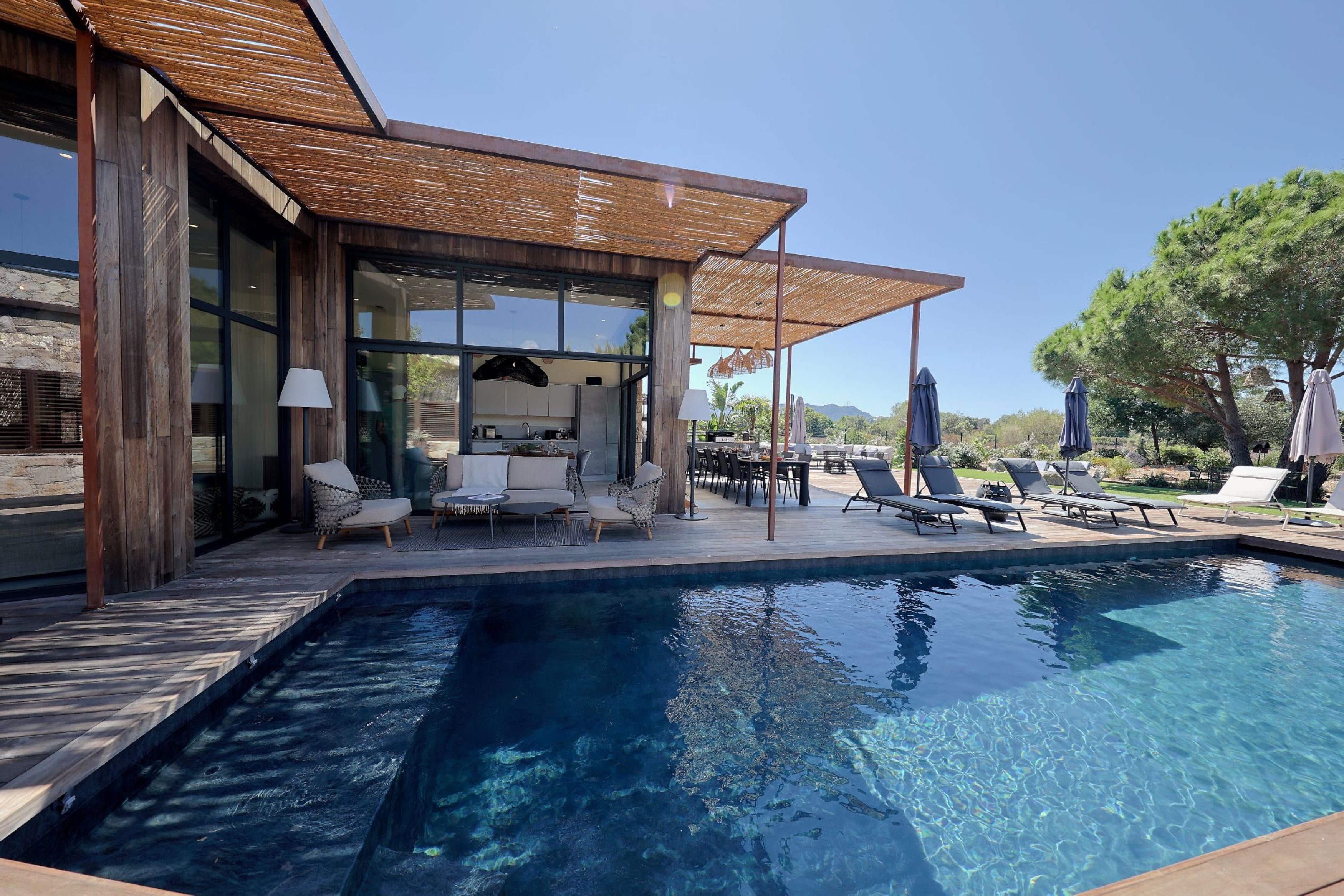 Zona de piscina exterior moderna amb gandules i zona d'seure coberta.