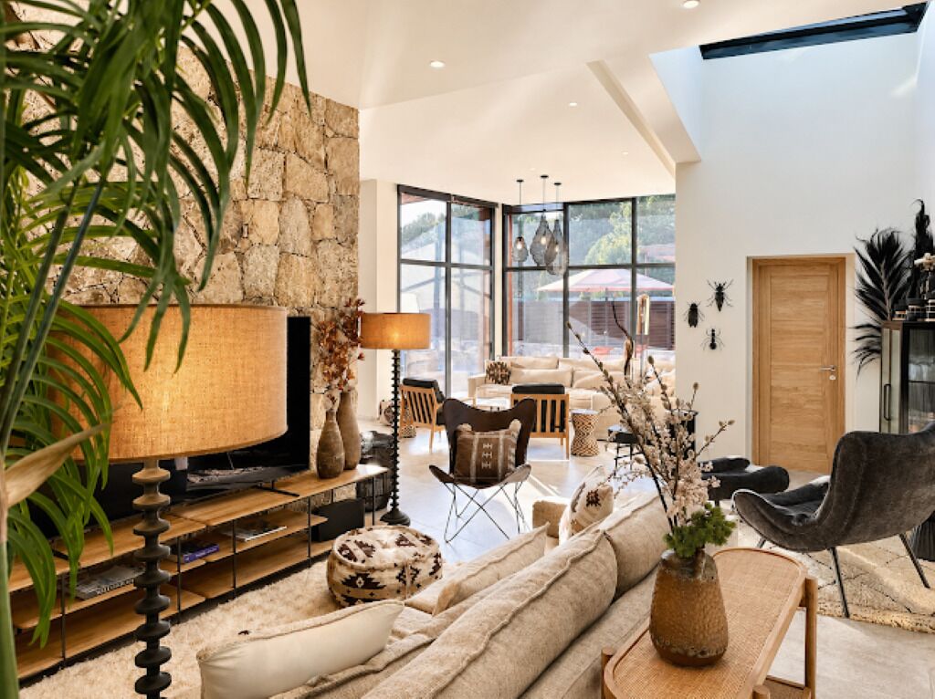 A modern living room with a stone wall, a television, and a variety of seating options including a sofa and chairs.