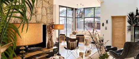 A modern living room with a stone wall, a television, and a variety of seating options including a sofa and chairs.