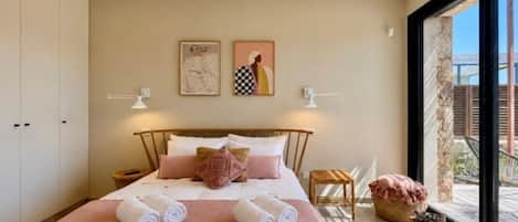 A bedroom with a bed, bedside tables, a window, and artwork on the wall.