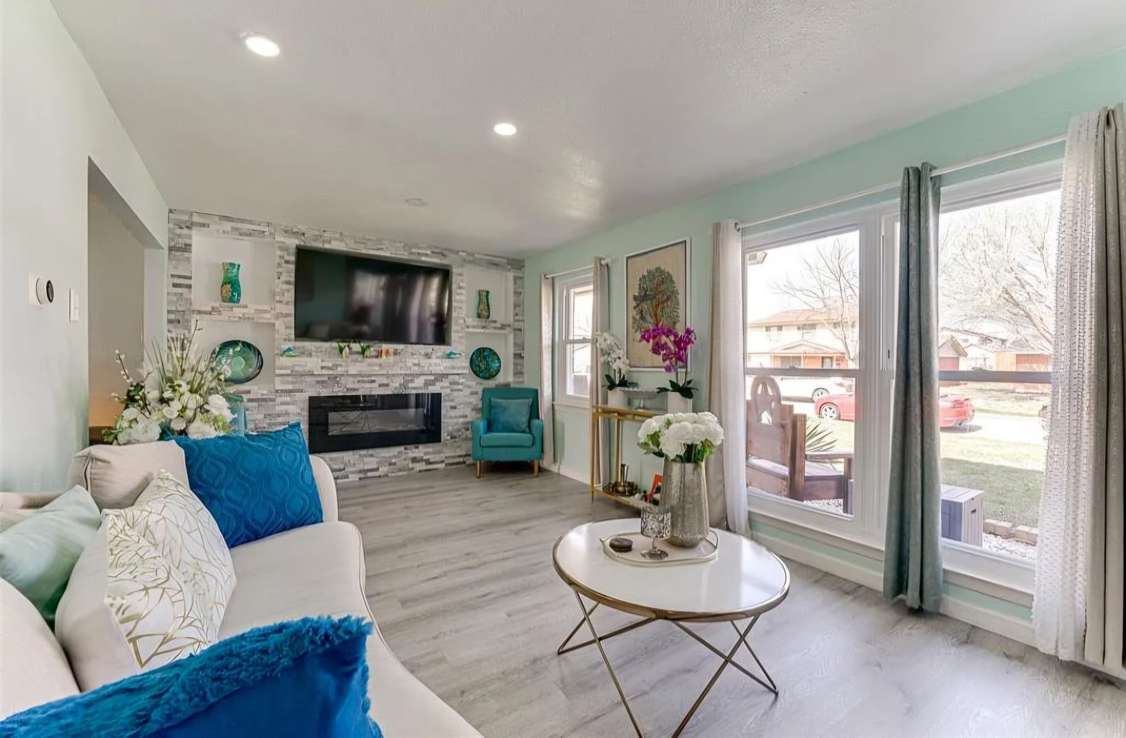 A living room with a fireplace, a sofa, a coffee table, and a television mounted on the wall.