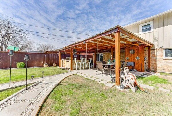A covered patio area with outdoor furniture and a barbecue grill.