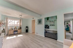 A spacious living area with a wooden floor, a built-in entertainment unit, and a coffee station.