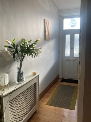 A hallway with a white radiator, a glass vase with flowers, and a door with a window. - Hens/Stags | Families | Corp | 14 guests £39pp (Cardiff)