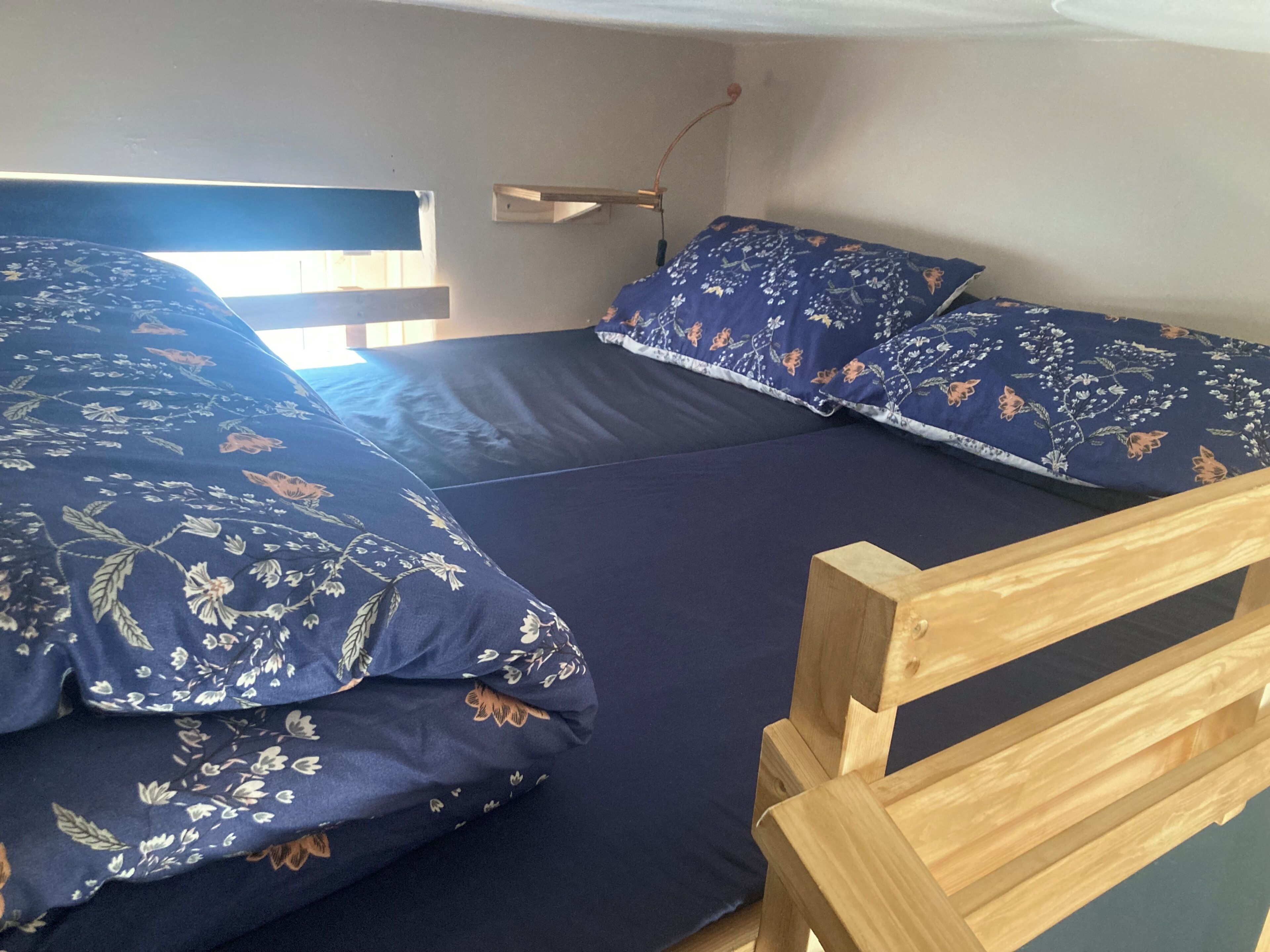 A bed with floral bedding, a wooden headboard, and a bedside table.