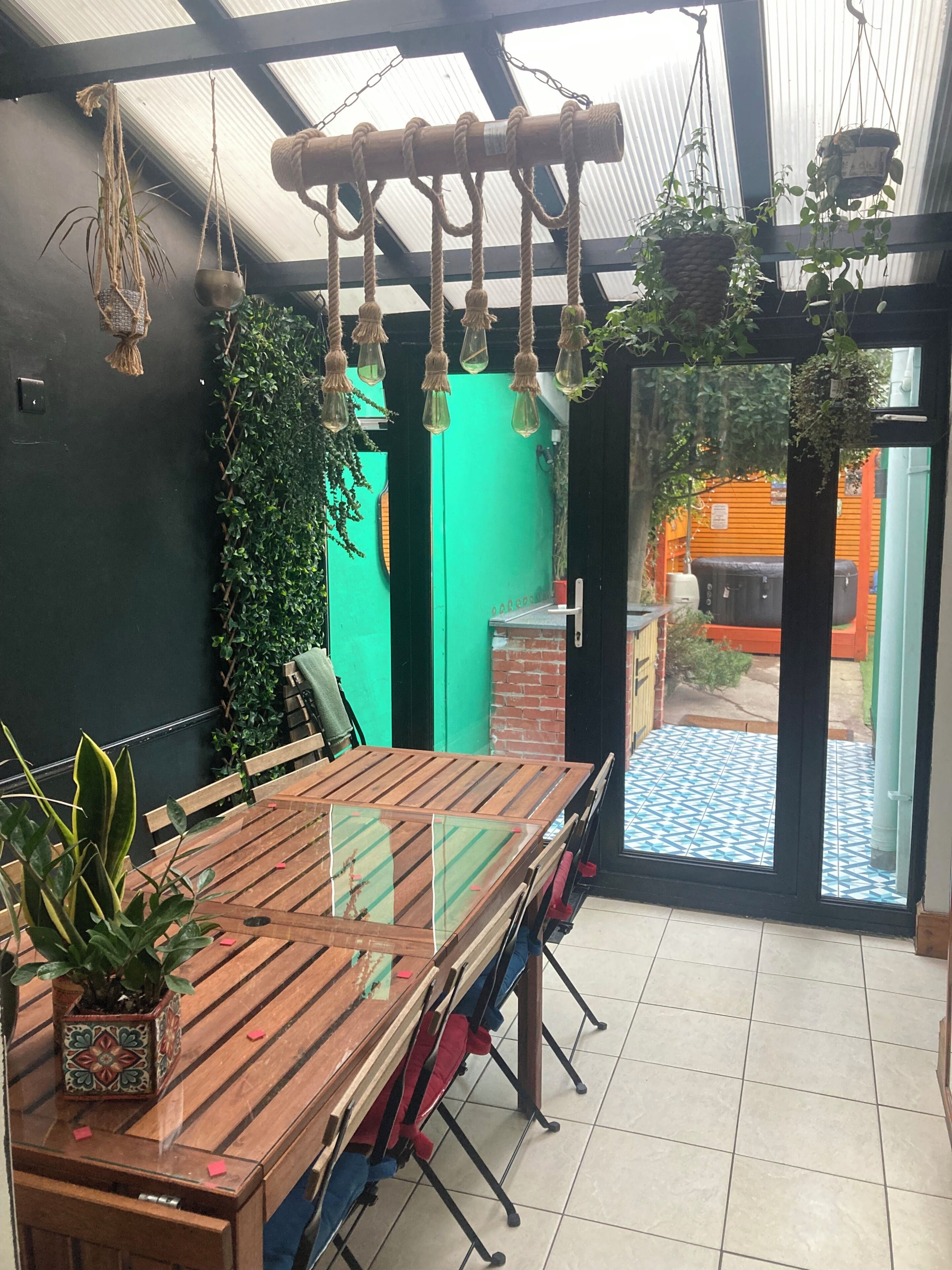 Een eetruimte met een houten tafel, stoelen en hangende planten.