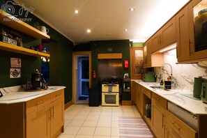 A kitchen with wooden cabinets, a stove, a sink, and a countertop with various items. - Hens/Stags | Families | Corp | 14 guests £39pp (Cardiff)
