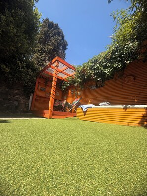 A wooden structure with a glass roof, possibly a gazebo, and a wall with a sign that reads 'MUSIC FEELING'. - Hens/Stags | Families | Corp | 14 guests £39pp (Cardiff)