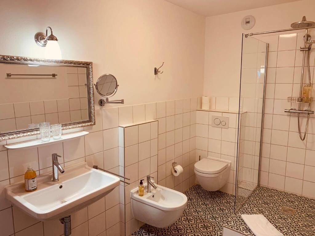 A bathroom with a sink, bidet, toilet, and a shower area.
