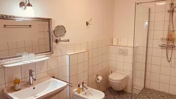 A bathroom with a sink, bidet, toilet, and a shower area.