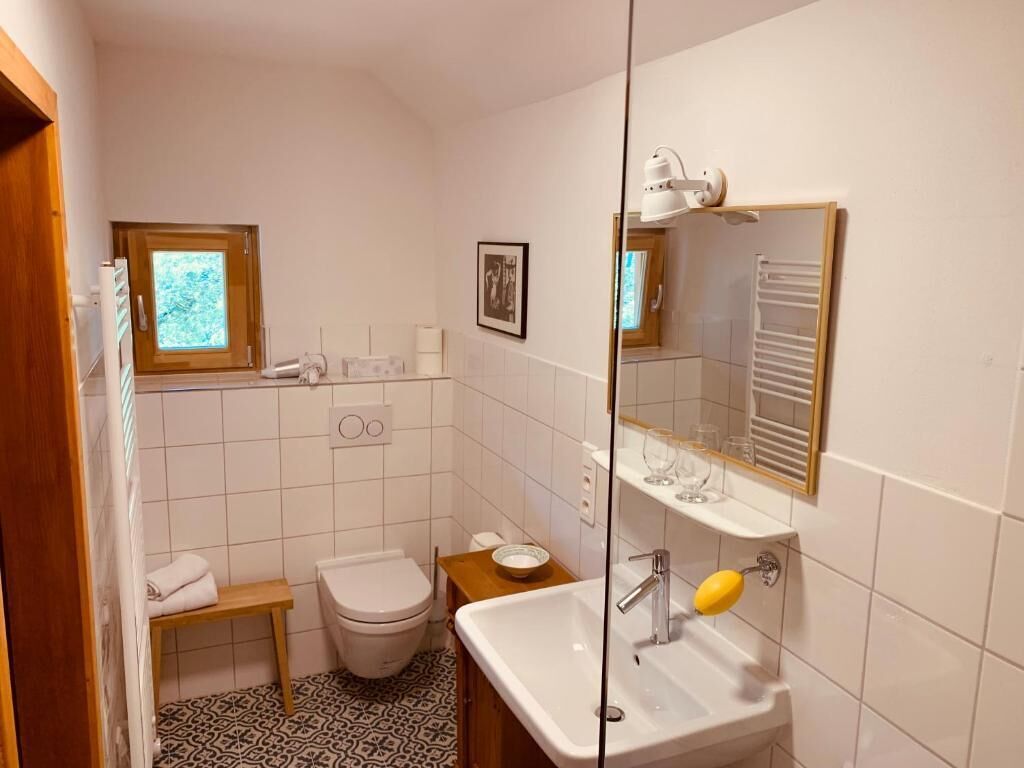 Ett litet badrum med toalett, handfat och ett fönster.