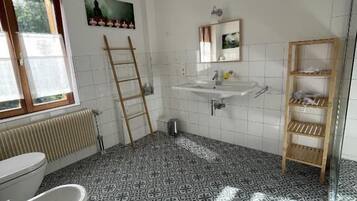A bathroom with a patterned floor, a toilet, a sink, a mirror, and a shelf.