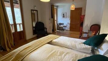A hotel room with two beds, a dining area, and a view of the outside.