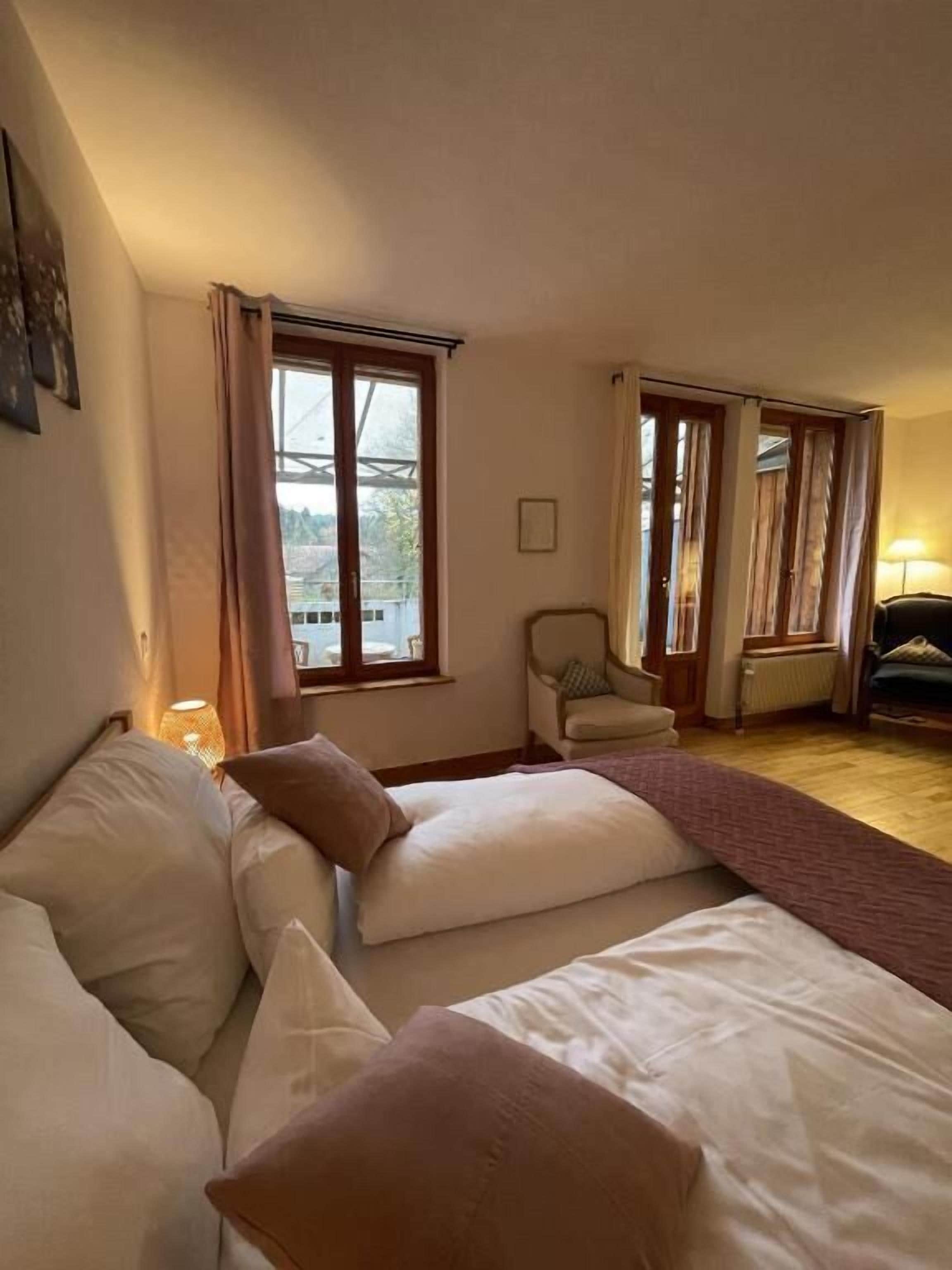 Un dormitorio con una cama, una silla y un ventanal.