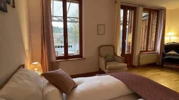Un dormitorio con una cama, una silla y un ventanal.