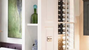 Una habitación con una alacena para vinos, un cuadro y una lámpara.