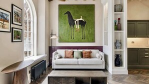 Una sala de estar moderna con un sofá blanco, una mesa de centro y un cuadro grande de un caballo.