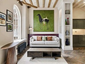 A modern living room with a white sofa, a coffee table, and a large painting of a horse. - Preacher's Yard Stylish Central York Apartment - Duplex 4 (York)