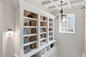 A room with white built-in bookshelves filled with books and decorative items, a hanging spherical light fixture, and a window with a view of buildings. - Preacher's Yard Stylish Central York Apartment - Duplex 4 (York)