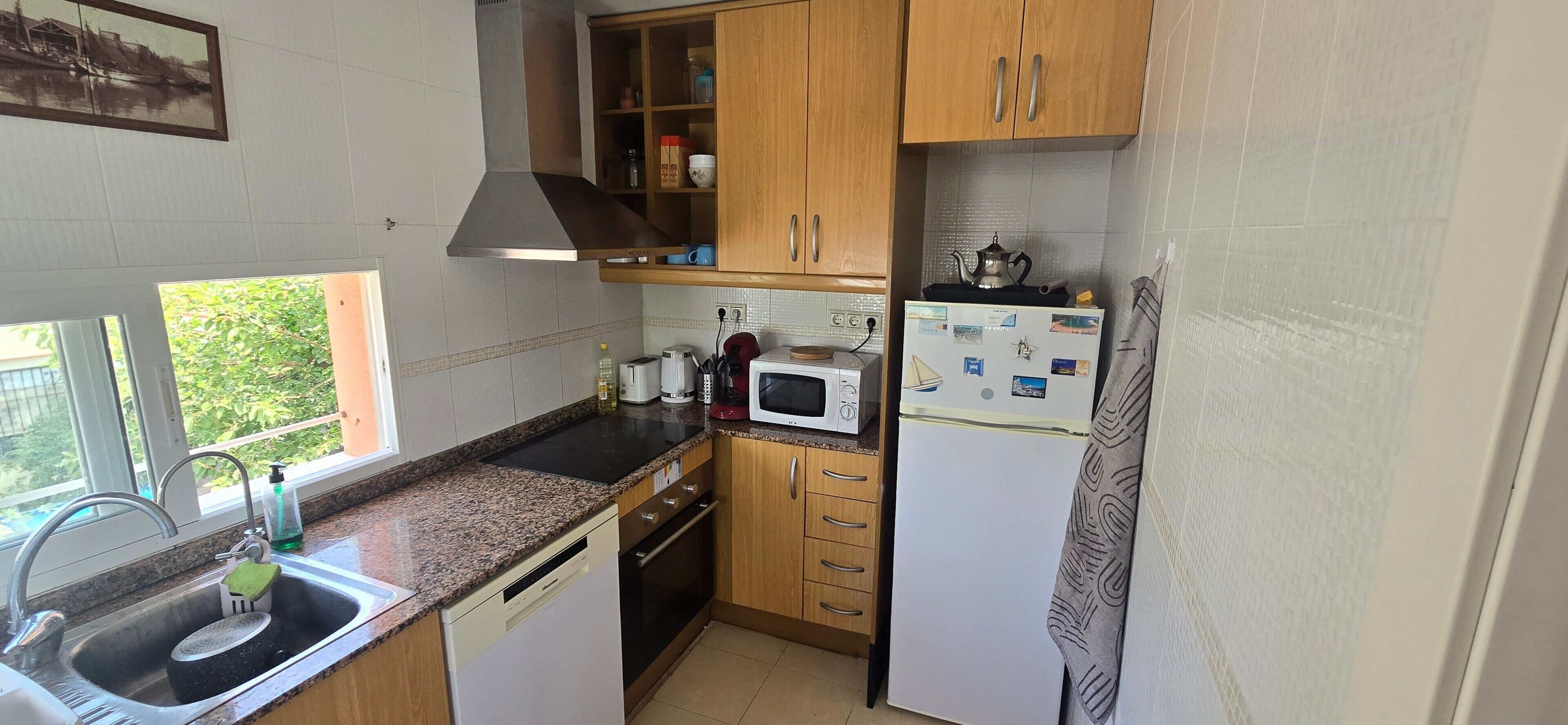 Une cuisine de taille réduite équipée d’un évier, d’une cuisinière, d’un four à micro-ondes et d’un réfrigérateur.