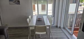 A dining area with a white table and chairs, a bowl of snacks, and a view through a sliding glass door. - 'Papa Luna' Apartment with Private Terrace, Wi-Fi, and Air Conditioning (Benicarló)
