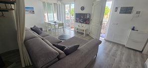 A modern living room with a sofa, a dining table, and a TV. - 'Papa Luna' Apartment with Private Terrace, Wi-Fi, and Air Conditioning (Benicarló)