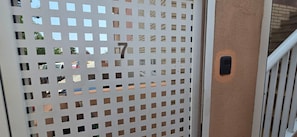 A metal gate with a series of square cutouts, a number '7' on the gate, and a small black object on the wall beside it. - 'Papa Luna' Apartment with Private Terrace, Wi-Fi, and Air Conditioning (Benicarló)