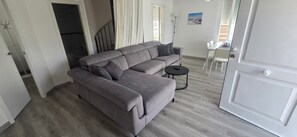 A grey sofa with a small round table, a white door, and a view of the outside through a window. - 'Papa Luna' Apartment with Private Terrace, Wi-Fi, and Air Conditioning (Benicarló)