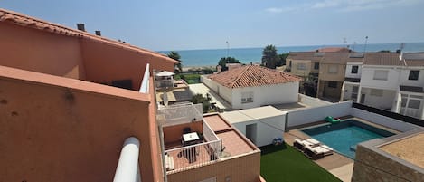 A residential area with a swimming pool, a view of the sea, and a clear sky.