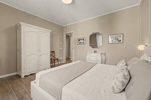 Een slaapkamer met een groot bed, een garderobe, een kaptafel en twee ingelijste foto's aan de muur.