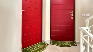 Deux portes rouges, avec un paillasson devant.