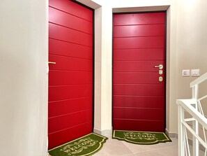 Zwei rote Türen mit Fußmatte davor.