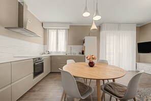 Een moderne keuken met een eethoek, een inbouwoven en een groot raam met gordijnen.