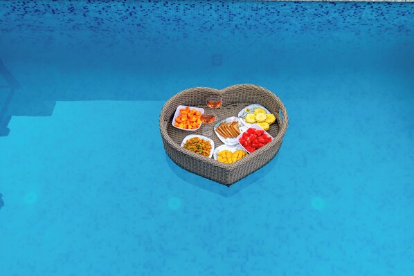 A heart-shaped wicker basket filled with various fruits and a glass of wine on a poolside. - Alaya Stays MS Valley Blossom 3BHK Villa (Dhanwala)