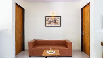 Una habitación con un sofá marrón, una pequeña mesa de madera con un objeto decorativo y un cuadro en la pared.