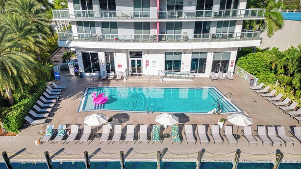 Ein Hotel mit Schwimmbad, Liegestühlen und einer Palme.