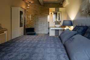 A bedroom with a bed, a desk, a chair, and a bathroom with a shower.