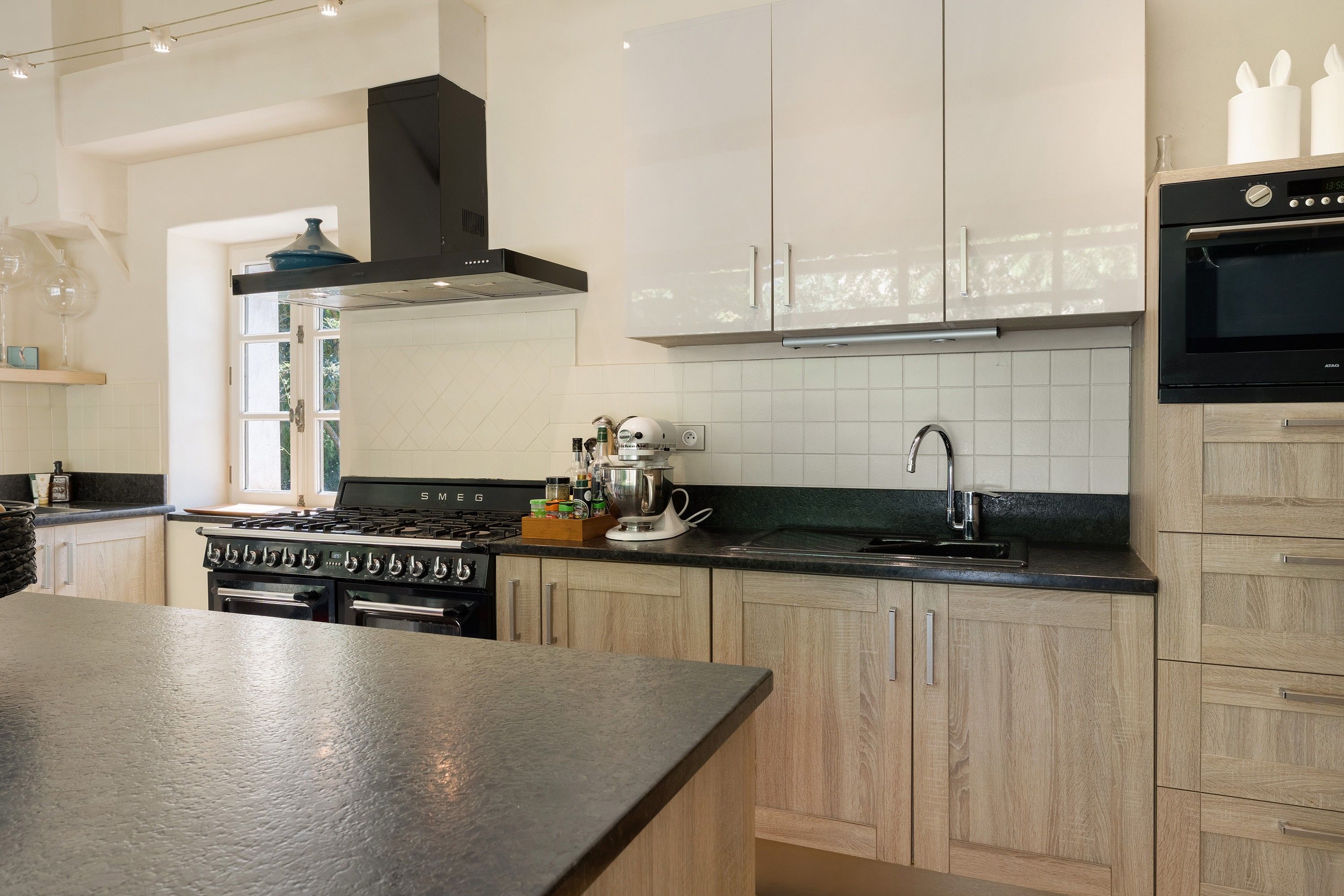 Una cocina moderna con una isla central, electrodomésticos de acero inoxidable y armarios de madera clara.