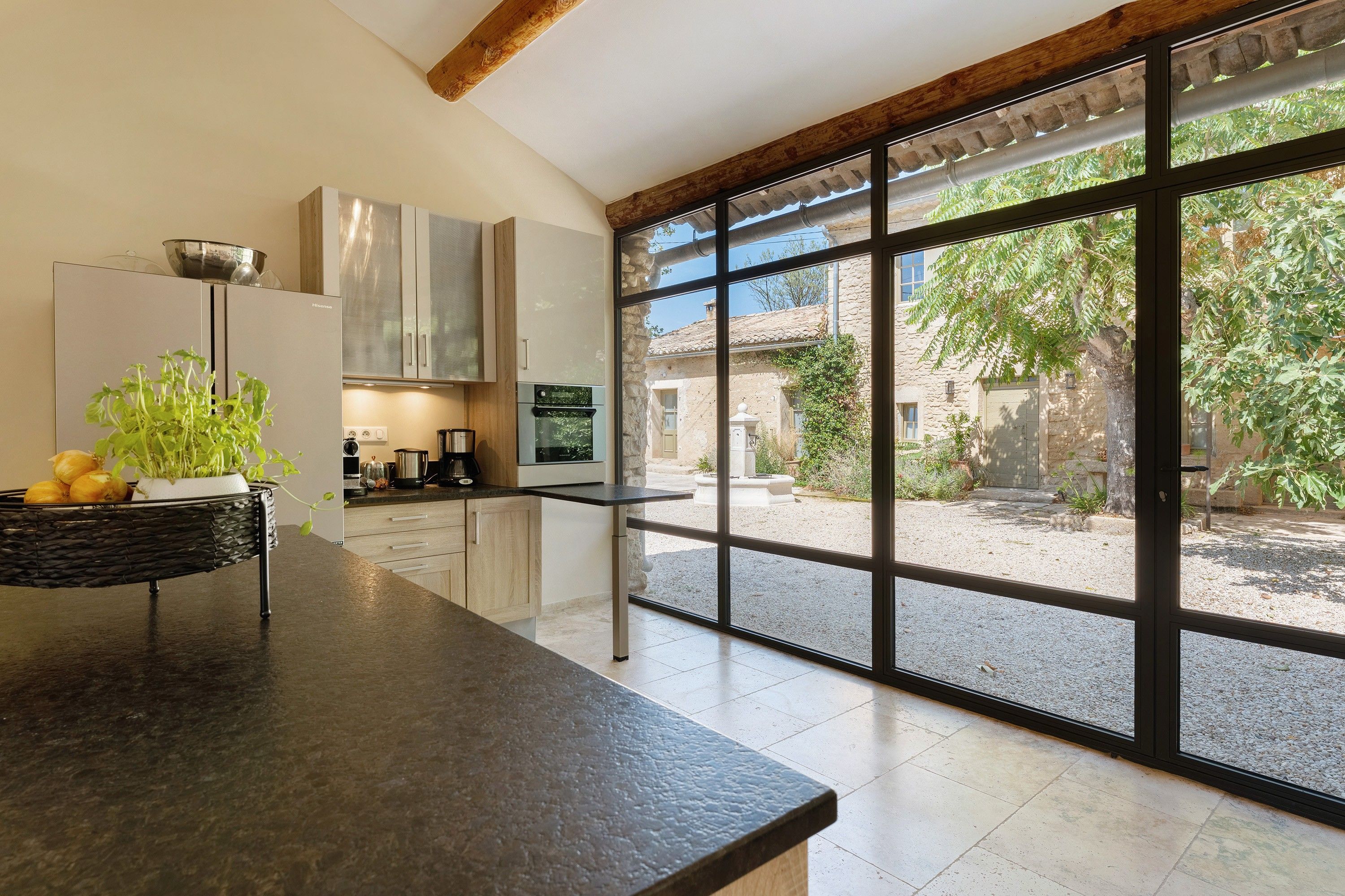 Una cocina moderna con un ventanal grande, una pared de piedra y vistas a un patio.