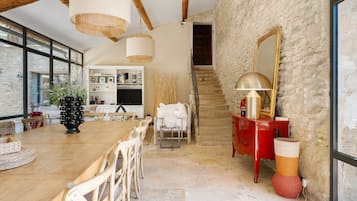 Ein geräumiger Essbereich mit Holztisch und -stühlen, im Hintergrund eine Küche und eine Treppe, die in einen oberen Bereich führt.