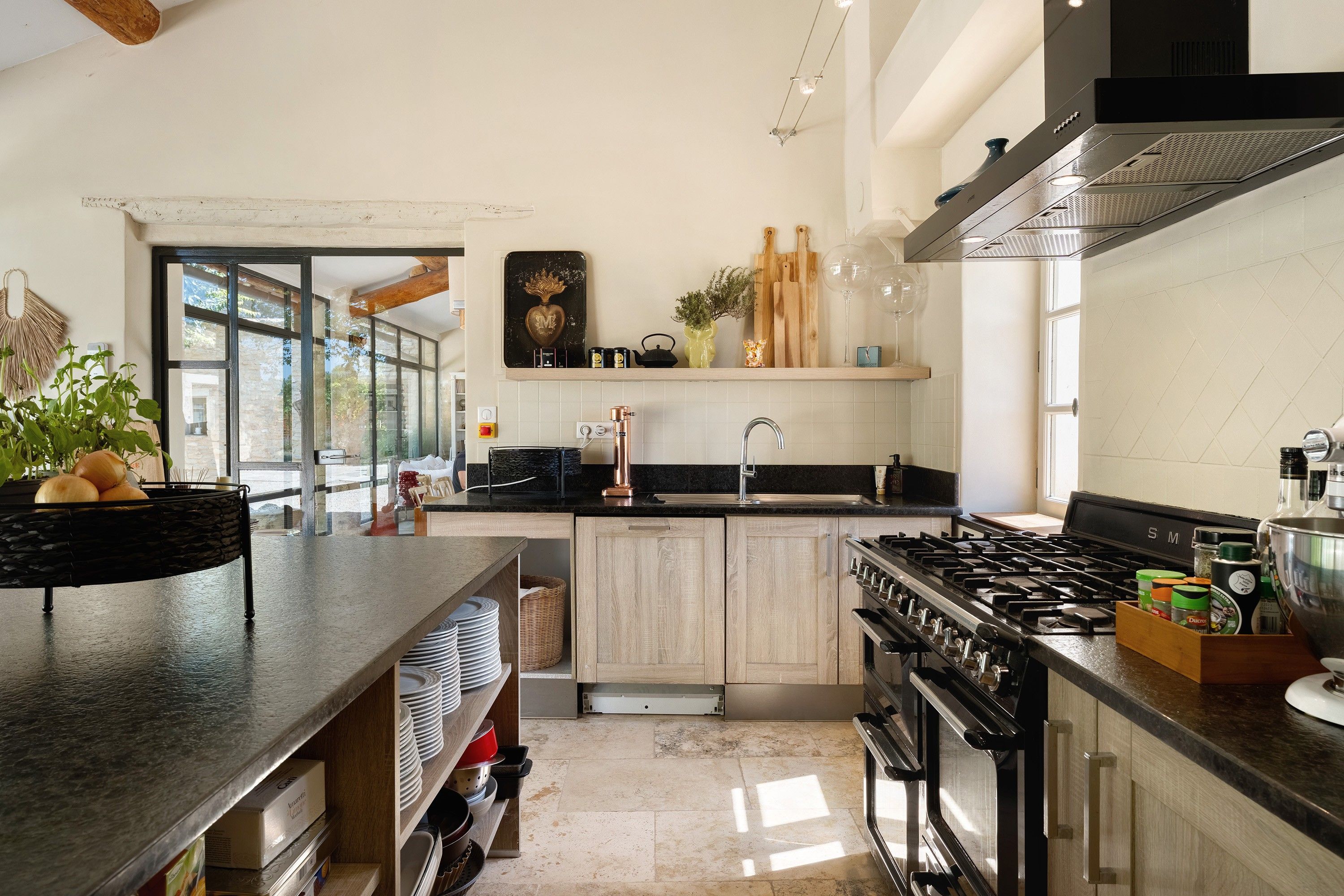 Una cocina moderna con una isla grande, electrodomésticos de acero inoxidable y vistas al exterior.