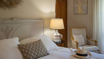 Quarto de hotel com uma cama, uma luminária, uma cadeira e um detalhe decorativo na parede.